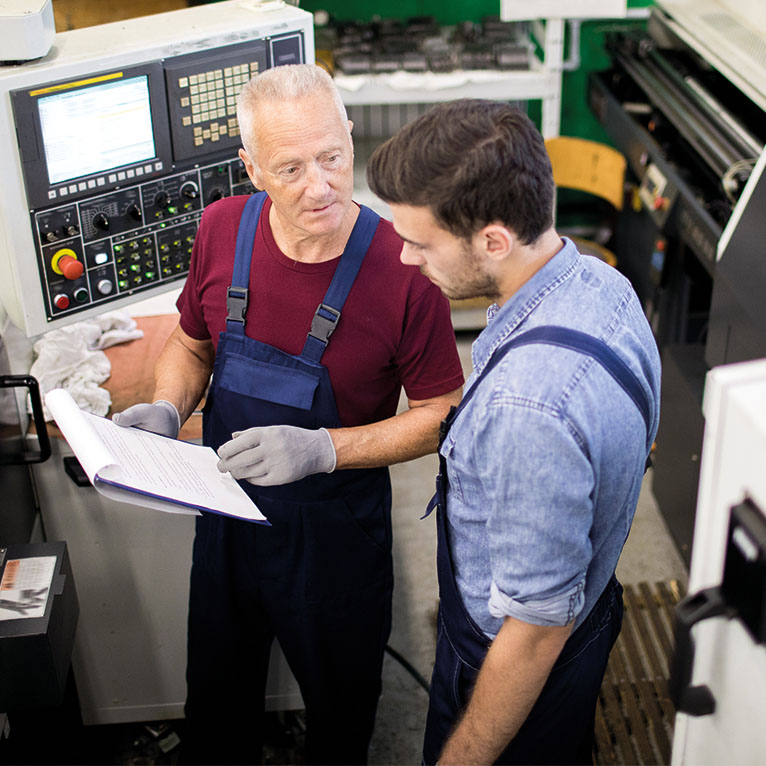 Knowledge retention: an experienced worker passes on his knowledge to a young colleague